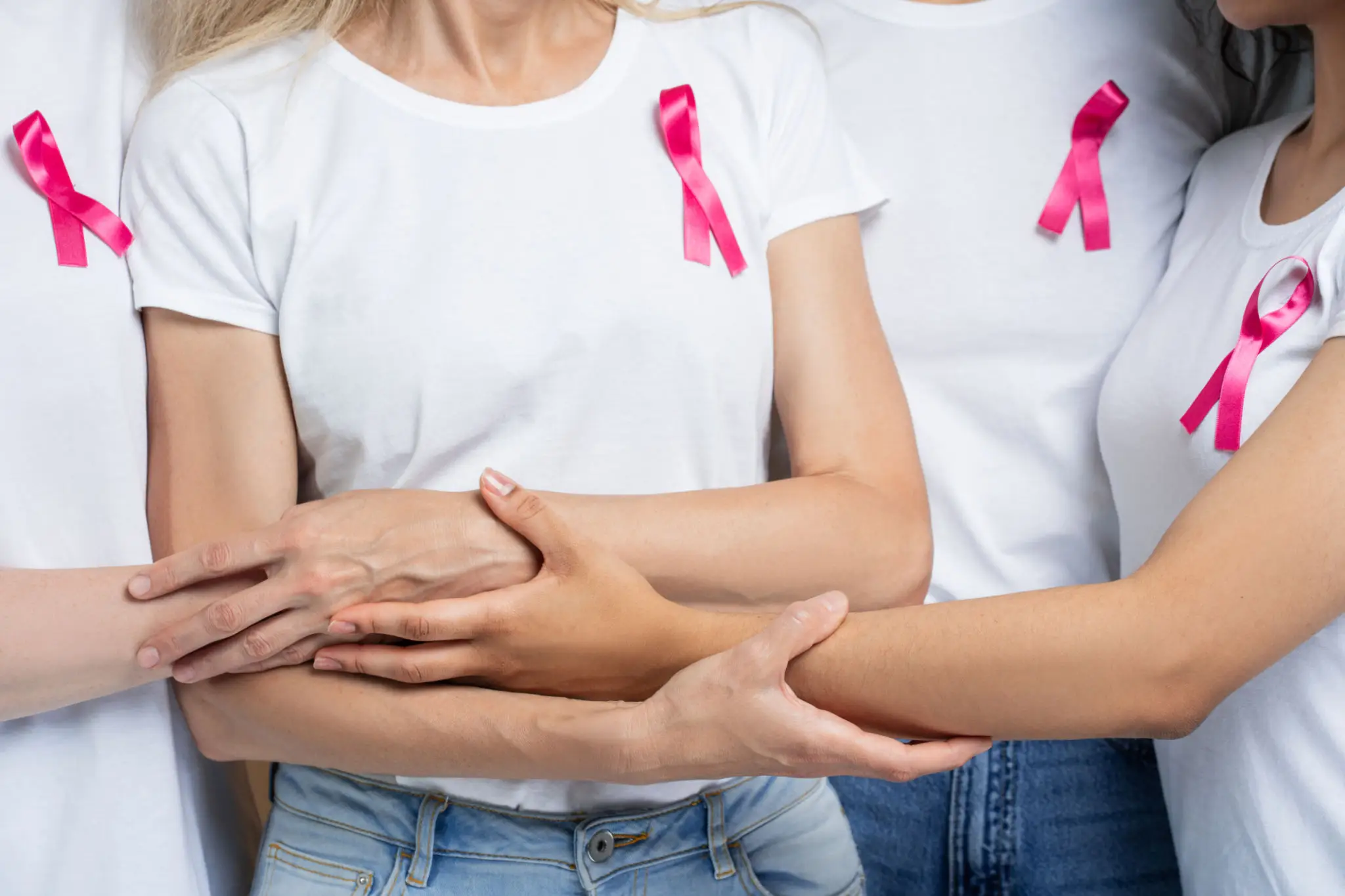Women in white shirts with pink ribbons.